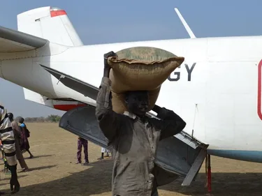 Foto van hulpverleners in Zuid-Sudan, die bezig zijn om hulpgoederen uit een vliegtuig te laden.