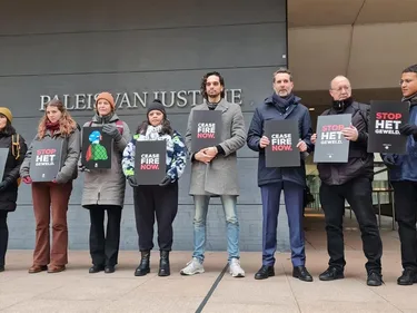 groep mensen die voor het paleis van justitie staat. ze houden borden omhoog met daarop de teksten "cease fire now" en "stop het geweld"
