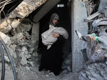 Palestijnse vrouw draagt overleden kind uit een verwoest gebouw.