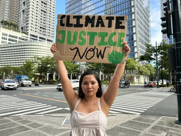Klimaatactivist Marinel houdt een bord met 'Climate Justice Now' omhoog