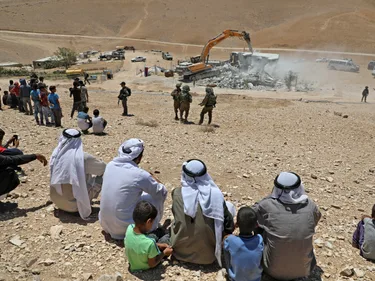 Bewoners kijken toe hoe Israëlische bulldozer een Palestijns huis sloopt