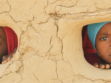 Jemen - beeld met kinderen nour en samar door gaten in muur