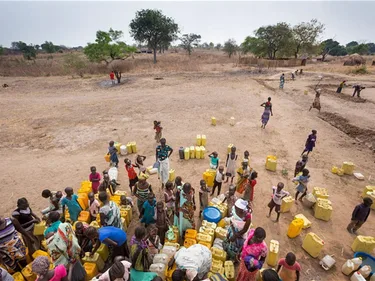 Een groep mensen met een groot aantal jerrycans om hen heen.