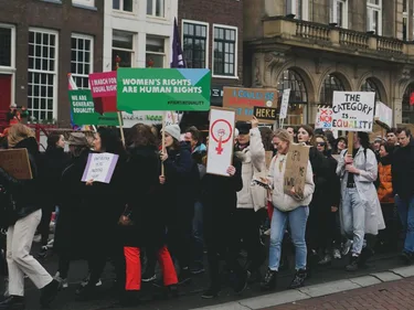 Foto van de vrouwenmars in Amsterdam. De demonstranten hebben borden met daarop teksten zoals "Women's rights are human rights".