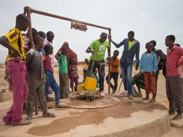 Foto van bewoners bij een waterpomp