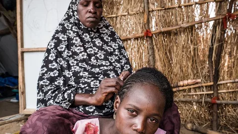 Hassana vlecht haren van vrouwen en meisjes in het dorp, om extra geld te verdienen.