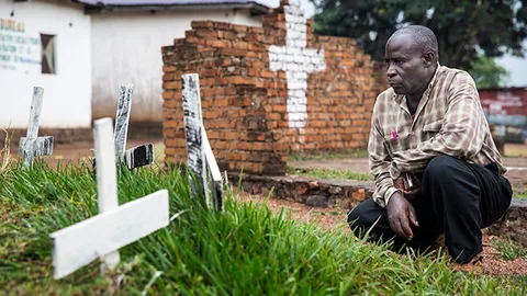 Man op zijn hurken voor graf