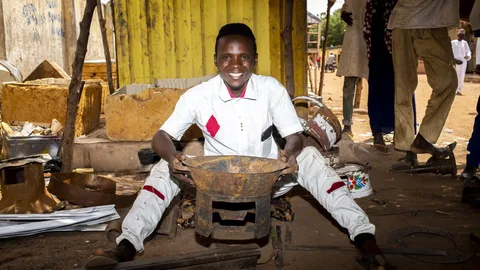 Salisu Mbeo houdt een ijzeren kooktoestel vast.