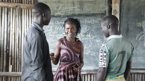 Een docent staat voor een schoolbord met twee leerlingen.