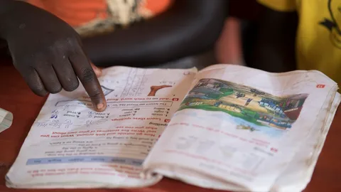 Iemand houdt zijn wijsvinger bij tekst in een schrift.