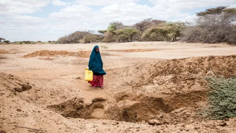 Halima loopt met een jerrycan over een droge vlakte.