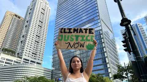 Marinel Sumook Ubaldo aan het protesteren en houdt bord omhoog met daarop Climate Justice Now.