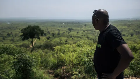 Foto van Oxfam-ingenieur Modeste Mirindi die uitkijkt op een groene, beboste vlakte in Congo.