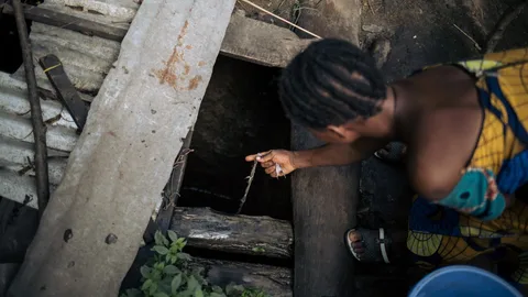 Rebaka haalt met een emmer en een touw water uit een put.