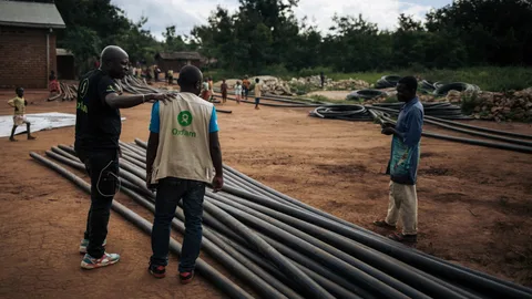 Modeste legt zijn hand op de schouder van een teamlid bij de aanleg van de waterleiding.