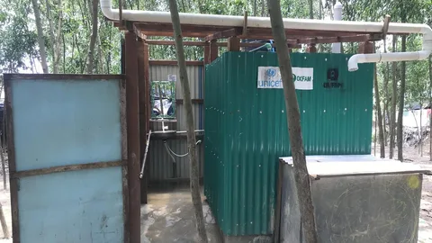 Een toiletgebouw van golfplaten met de logo's van UNICEF en Oxfam.