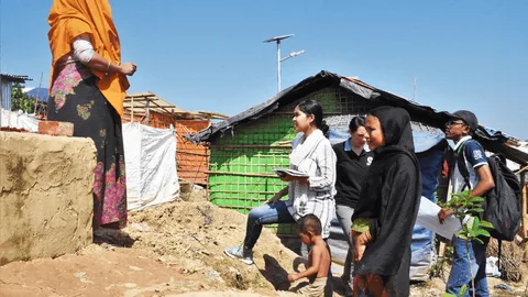 Een groepje mensen kijkt naar een vrouw die op een verhoging staat.
