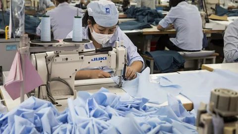 Vrouw aan het naaien in een kledingfabriek in Vietnam