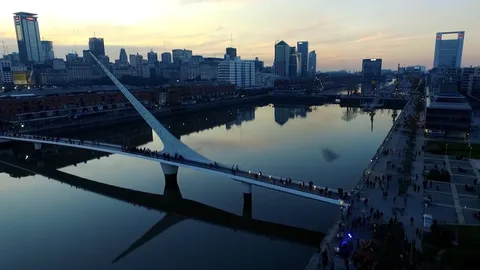 Een brug over een rivier met een skyline op de achtergrond.