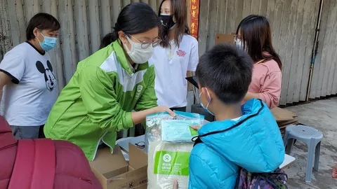 Een vrouw deelt rijst uit aan een jongetje.