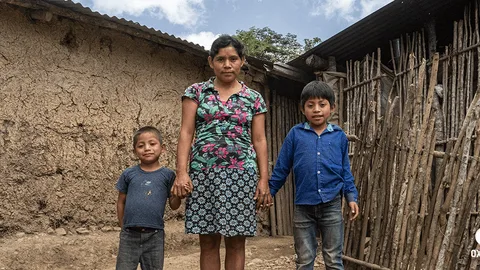 Een vrouw houdt de handen van twee jongetjes vast.