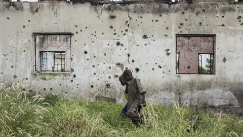 Kinderen lopen voor kapotte huizen.