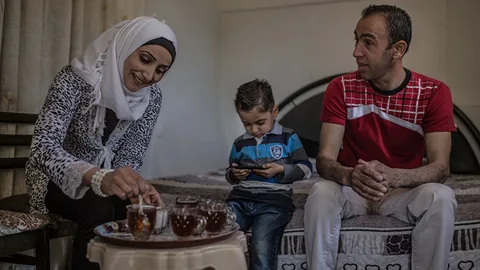 Fatem, haar man en haar zoontje zitten om een tafeltje waarop thee staat.