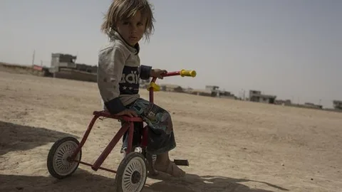 Foto van de 2-jarige Jasm die op haar driewieler door een vluchtelingenkamp rijdt, zo'n 70 kilometer ten zuiden van Mosul.