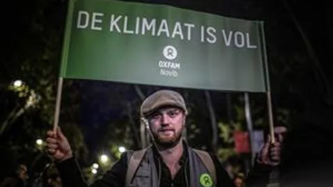 Foto van Klimaatcampaigner Tim Zijlstra. Hij houdt een bord omhoog met de tekst "De Klimaat Is Vol"