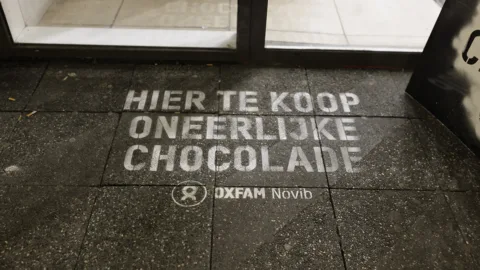 Green graffiti voor een supermarktdeur waarop 'Hier te koop oneerlijk chocolade'