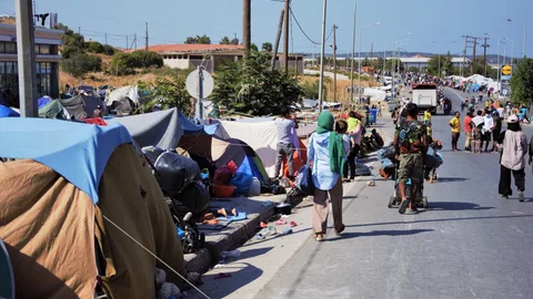 Tenten van vluchtelingen op de stoep naast een weg.