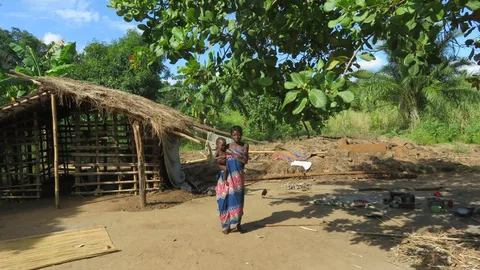 Moeder en kind staan voor een hut.