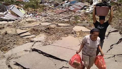 Vrouw en man tussen het puin met zakken levensmiddelen.