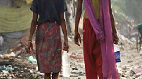 Twee mensen in een sloppenwijk van achteren gezien.