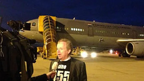 SHO-actievoorzitter Henri van Eeghen wordt geinterviewd voor een tv-camera. Op de achtergrond staat een groot vliegtuig.