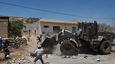Een Israëlische bulldozer veegt de blokkade weg die Palestijnse demonstranten opwierpen bij Nablus.