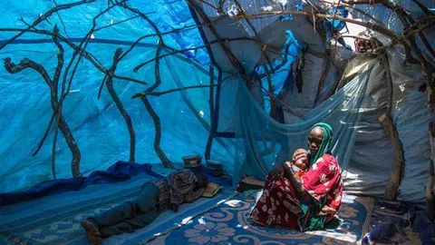 Fatma zit in een tent en houdt een kindje vast. Naast haar ligt iemand te slapen.