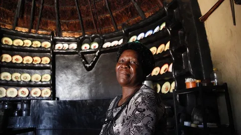 Marjory in haar huis. Op de achtergrond kasten met bordjes erin.