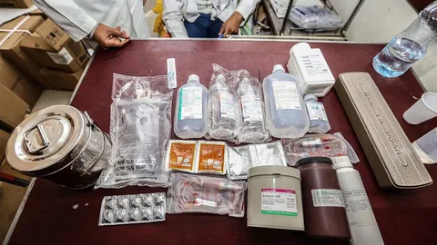 Foto van medisch personeel en medicijnen uitgespreid op een tafel.