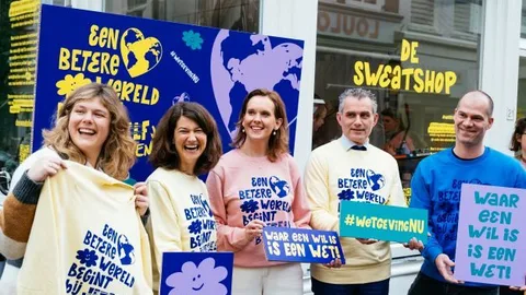 Medewerkers van Oxfam voor de 'sweatshop' houden een bordjes vast met daarop de tekst: Waar een wil is, is een wet!