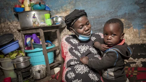 Beatrice houdt een jongetje vast. Achter haar staan potten en pannen.