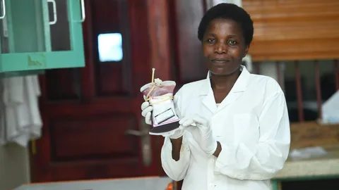 Laboratoriummedewerkster houdt een zak bloed vast in het regionale ziekenhuis Atutur in Kumi, waar op dat moment slechts vier zakken bloed op voorraad zijn.