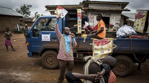 Foto van man met microfoon die in zijn hand een pamflet omhooghoudt.