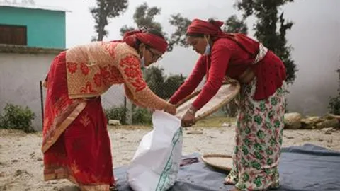 Two women put seeds in a bag.