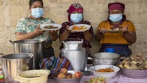 Three women showing plates with food.