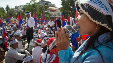 A woman speaking into a microphone in front of a crowd.