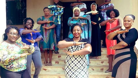 Foto van een groep vrouwen en mannen die met hun armen het "is gelijk" teken uitbeelden