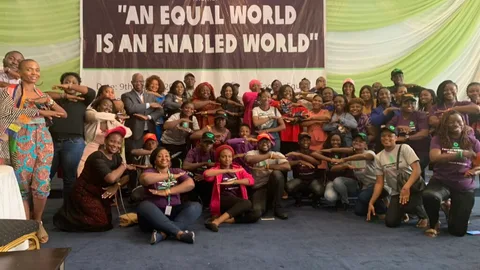 Foto van een groep mensen op vrouwendag. Ze staan voor een spandoek met de tekst "An equal world is an enabled world"
