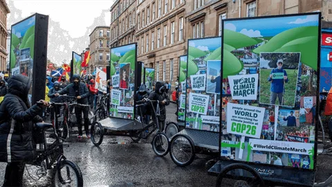People ride through the streets with large protest signs attached to bicycle frames.