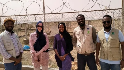 Mawlid, Nienke, Susan, Teferi en Ahmed staan voor een hek met prikkeldraad.